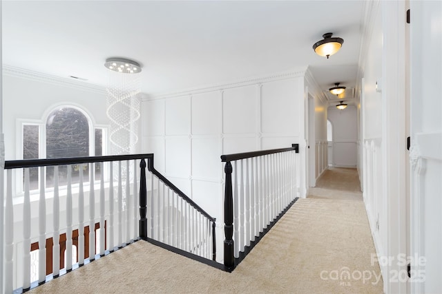 corridor with ornamental molding and light colored carpet