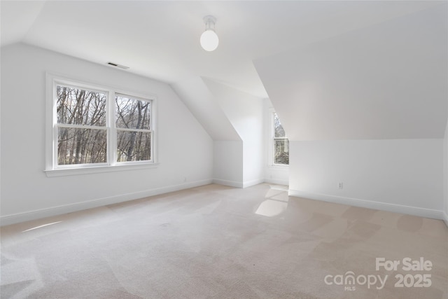 bonus room with light colored carpet and vaulted ceiling