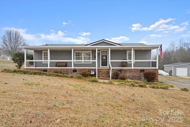 view of front of home featuring an outbuilding, a garage, covered porch, and a front yard