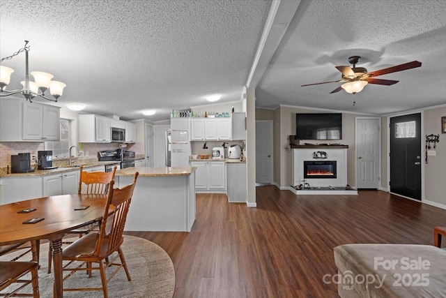 dining room with vaulted ceiling, dark hardwood / wood-style floors, ceiling fan with notable chandelier, sink, and a textured ceiling