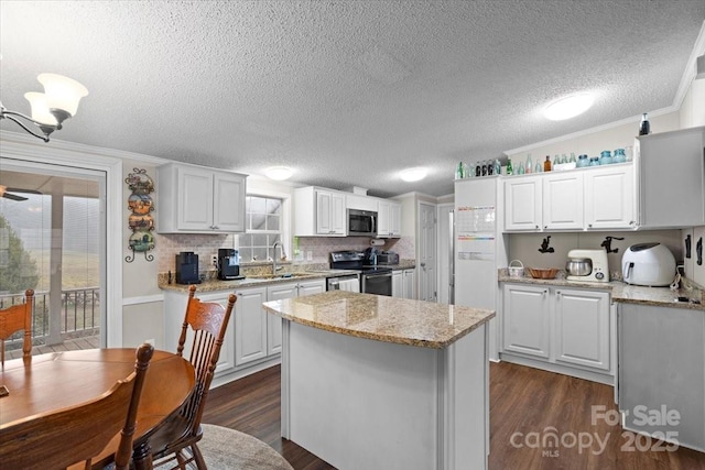 kitchen with dark hardwood / wood-style floors, stainless steel appliances, a center island, and white cabinets