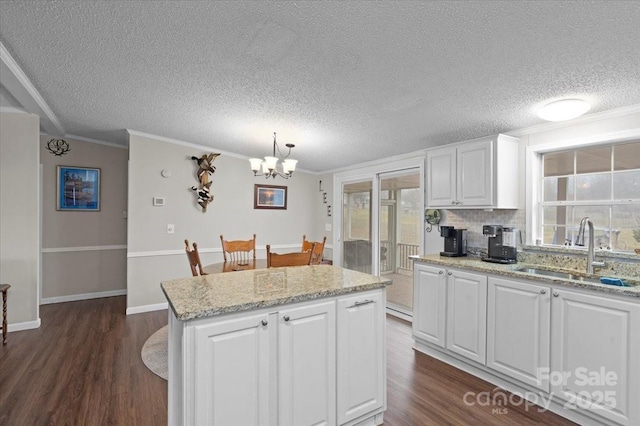 kitchen featuring pendant lighting, sink, white cabinetry, dark hardwood / wood-style floors, and a kitchen island