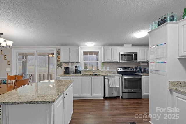 kitchen featuring sink, white cabinetry, appliances with stainless steel finishes, dark hardwood / wood-style floors, and light stone countertops