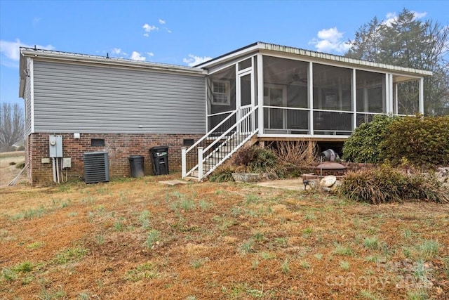 back of property with a yard, a sunroom, and central air condition unit