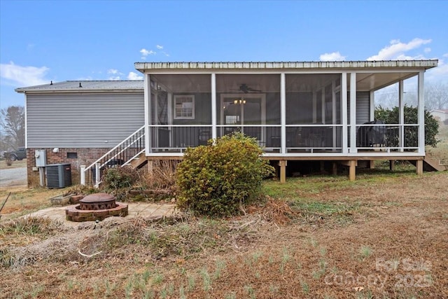 back of house with central AC unit, a sunroom, and an outdoor fire pit