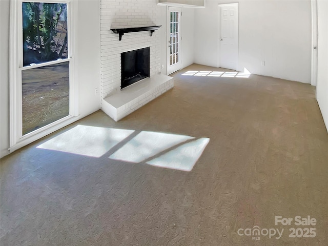 unfurnished living room with a brick fireplace and carpet floors