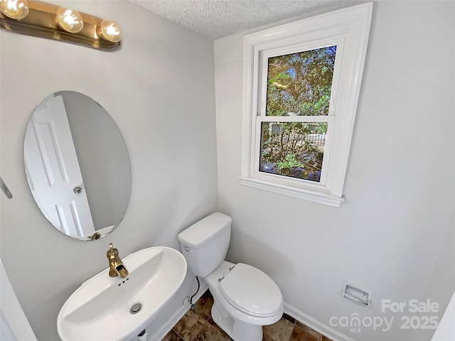 bathroom with toilet, sink, and a textured ceiling