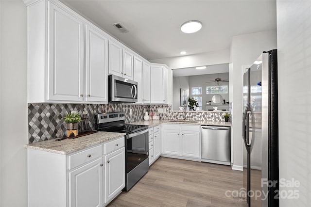 kitchen with sink, stainless steel appliances, light hardwood / wood-style floors, decorative backsplash, and white cabinets