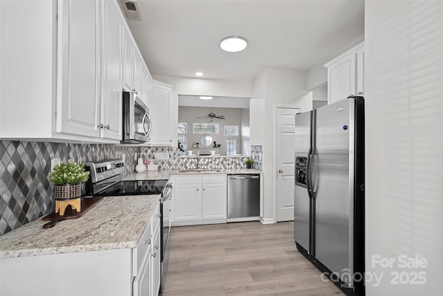 kitchen with white cabinetry, appliances with stainless steel finishes, light stone countertops, and sink