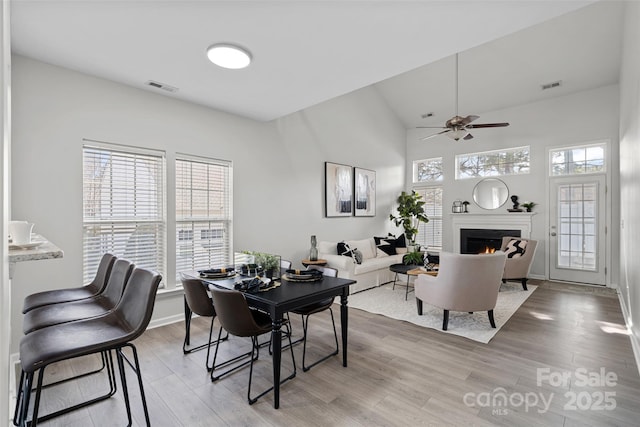 dining room with ceiling fan, a high ceiling, and light wood-type flooring