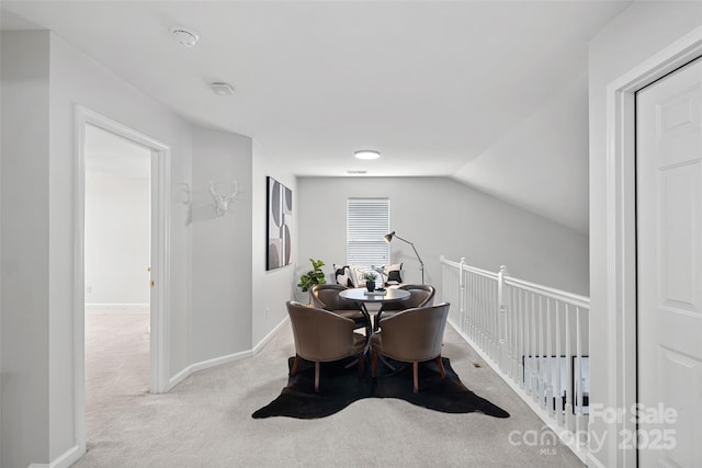 dining space featuring lofted ceiling and light colored carpet