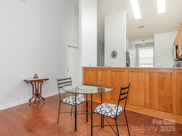 dining room featuring a towering ceiling and dark hardwood / wood-style floors