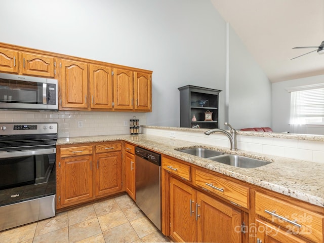 kitchen with sink, kitchen peninsula, stainless steel appliances, light stone countertops, and decorative backsplash