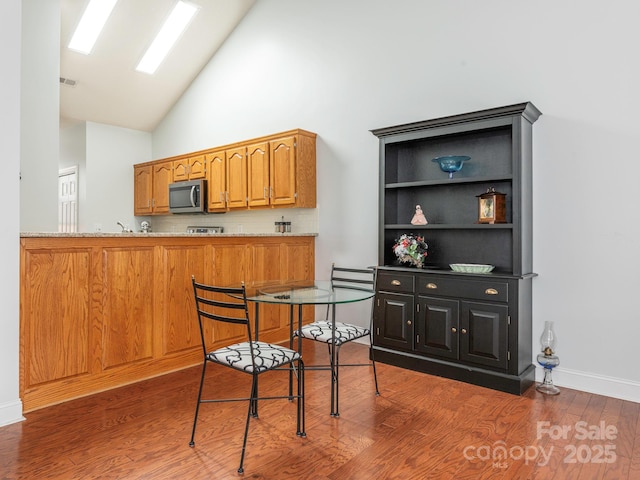 kitchen with light stone counters, dark hardwood / wood-style flooring, and high vaulted ceiling