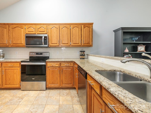 kitchen with tasteful backsplash, lofted ceiling, appliances with stainless steel finishes, and sink