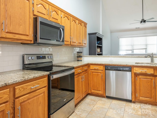 kitchen with sink, vaulted ceiling, ceiling fan, stainless steel appliances, and decorative backsplash