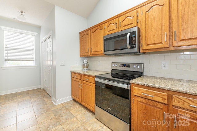 kitchen featuring light stone counters, backsplash, and appliances with stainless steel finishes