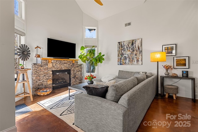 living room with hardwood / wood-style flooring, a stone fireplace, high vaulted ceiling, and a healthy amount of sunlight