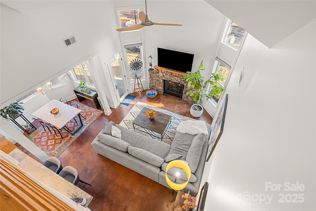 living room featuring ceiling fan, a towering ceiling, hardwood / wood-style floors, and a fireplace