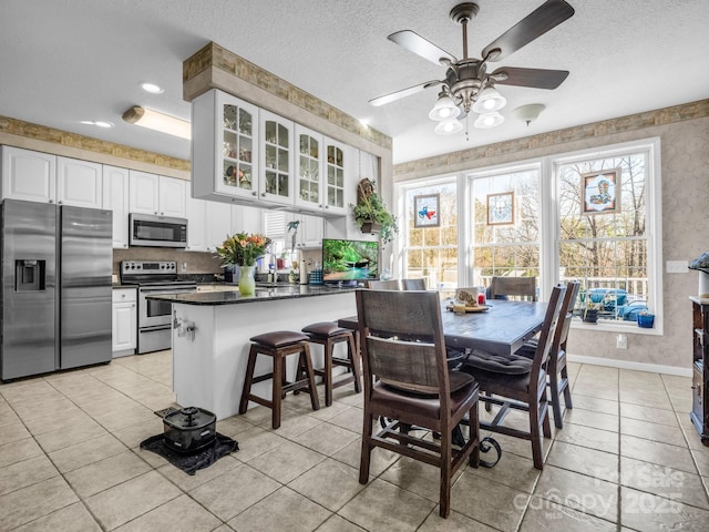 dining room with ceiling fan, light tile patterned floors, and a textured ceiling