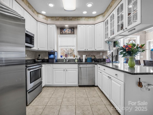 kitchen with dark stone countertops, sink, stainless steel appliances, and white cabinets