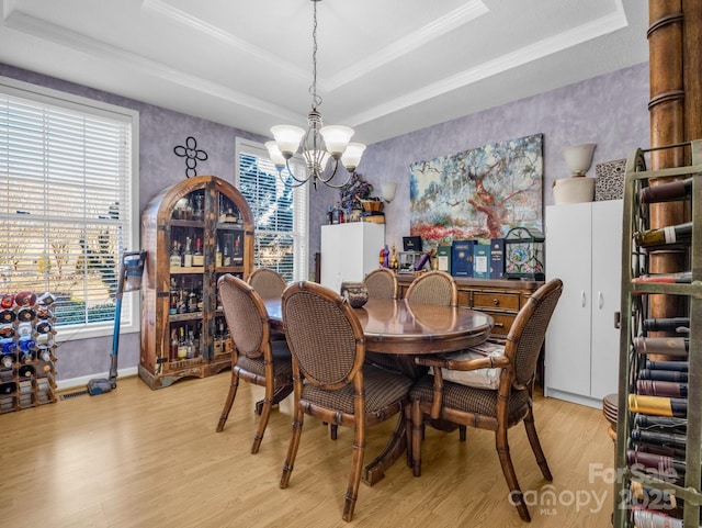 dining space featuring an inviting chandelier, a tray ceiling, and light wood-type flooring