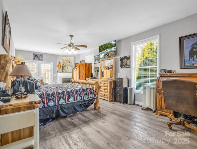 bedroom with ceiling fan, light hardwood / wood-style floors, and multiple windows