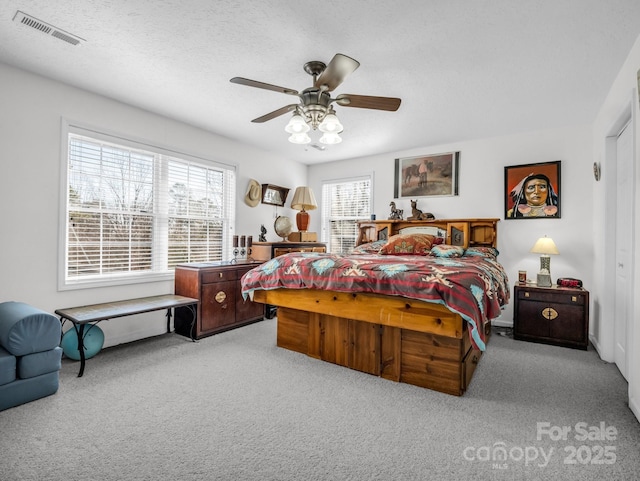 carpeted bedroom with ceiling fan and a textured ceiling