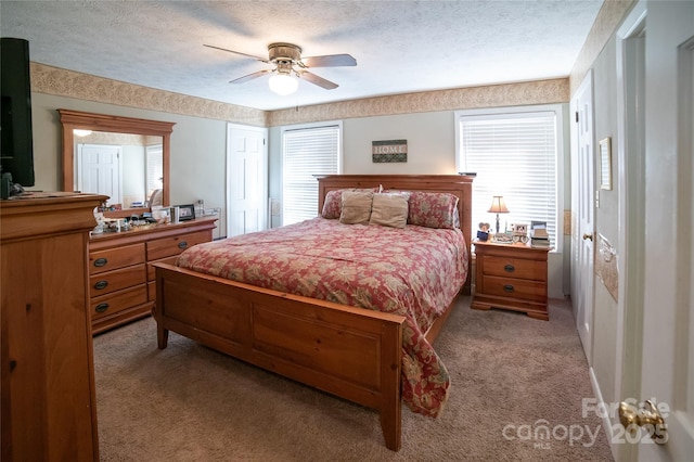 carpeted bedroom featuring ceiling fan, multiple windows, and a textured ceiling