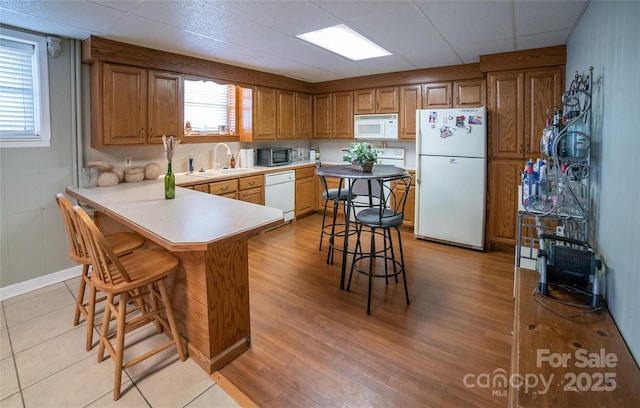 kitchen with a kitchen breakfast bar, plenty of natural light, sink, and white appliances