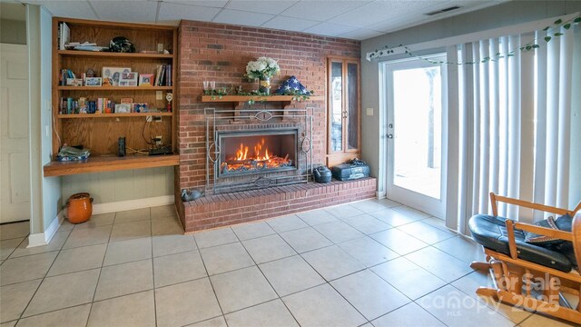 tiled living room featuring a fireplace and a paneled ceiling