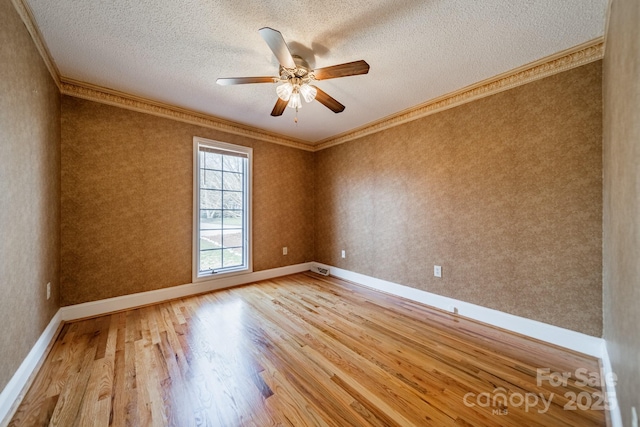 unfurnished room with wood finished floors, wallpapered walls, ceiling fan, ornamental molding, and a textured ceiling