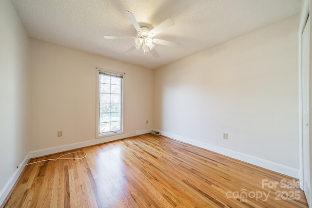 empty room with light wood finished floors, ceiling fan, a textured ceiling, and baseboards