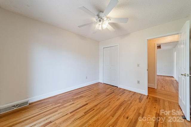 unfurnished bedroom featuring visible vents, baseboards, light wood-type flooring, a closet, and a ceiling fan
