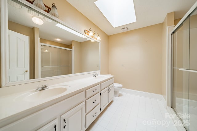 bathroom featuring a sink, toilet, a stall shower, and a skylight