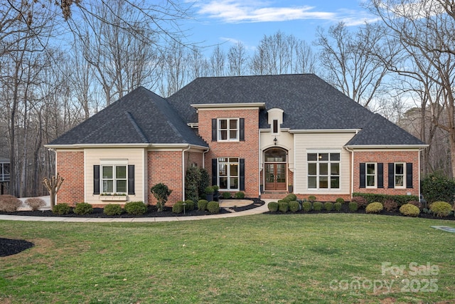 view of front of property featuring a front yard, brick siding, and roof with shingles