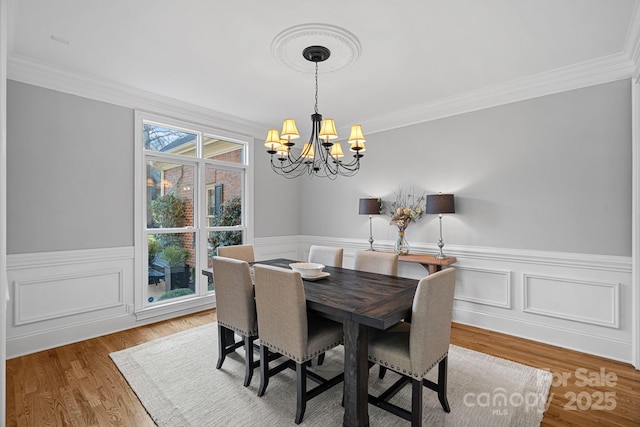 dining room with a wainscoted wall, an inviting chandelier, and wood finished floors