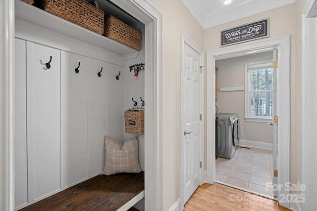 mudroom featuring baseboards, wood finished floors, washing machine and dryer, and crown molding