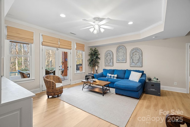 living area with crown molding, light wood finished floors, visible vents, ceiling fan, and baseboards