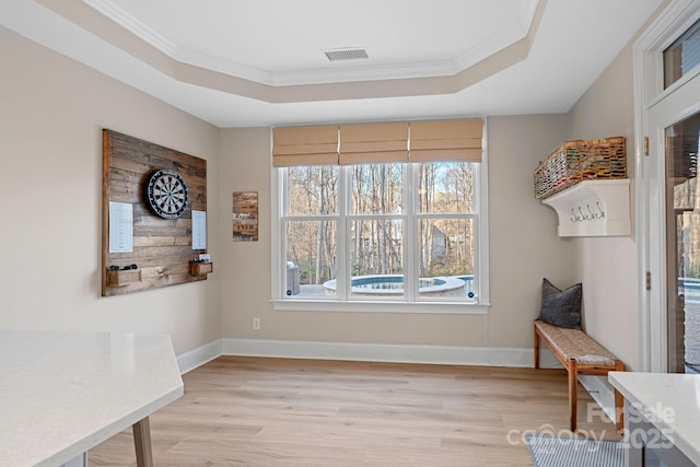 sitting room with light wood-style floors, visible vents, and a tray ceiling