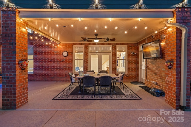 dining room featuring ceiling fan and brick wall