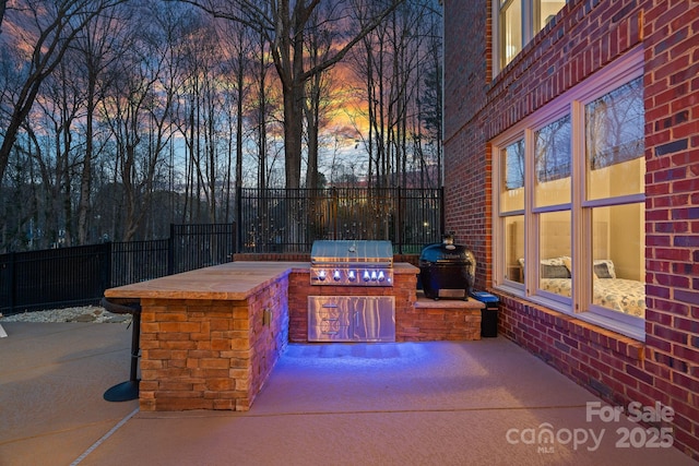 view of patio with a grill, fence, and exterior kitchen