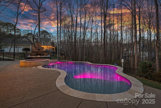 view of pool featuring a warm lit fireplace, a pool with connected hot tub, and a patio