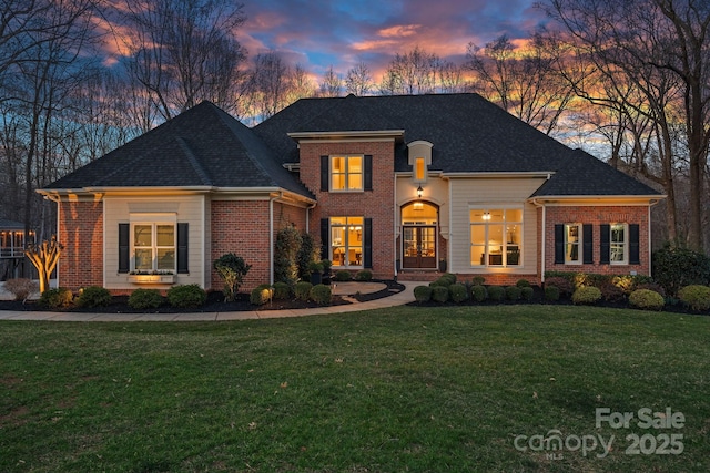 view of front of home with brick siding and a yard