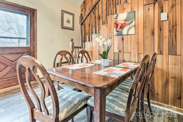 dining space with hardwood / wood-style floors and wooden walls