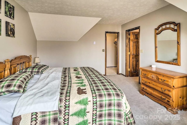 bedroom featuring lofted ceiling, a spacious closet, light colored carpet, and a textured ceiling