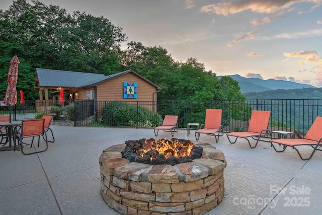 patio terrace at dusk featuring a mountain view and a fire pit