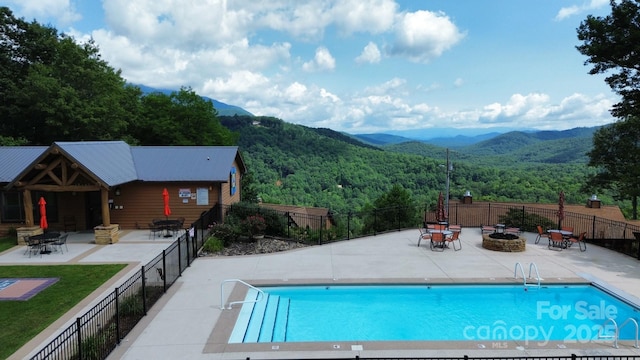 view of pool with a mountain view, a patio area, and an outdoor fire pit