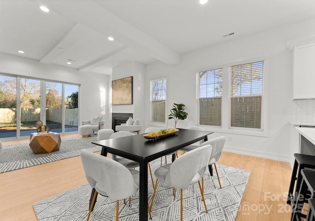 dining area with light hardwood / wood-style flooring and beam ceiling