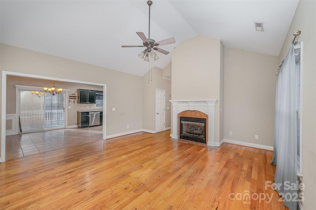 unfurnished living room with a fireplace, high vaulted ceiling, light wood-type flooring, and ceiling fan with notable chandelier